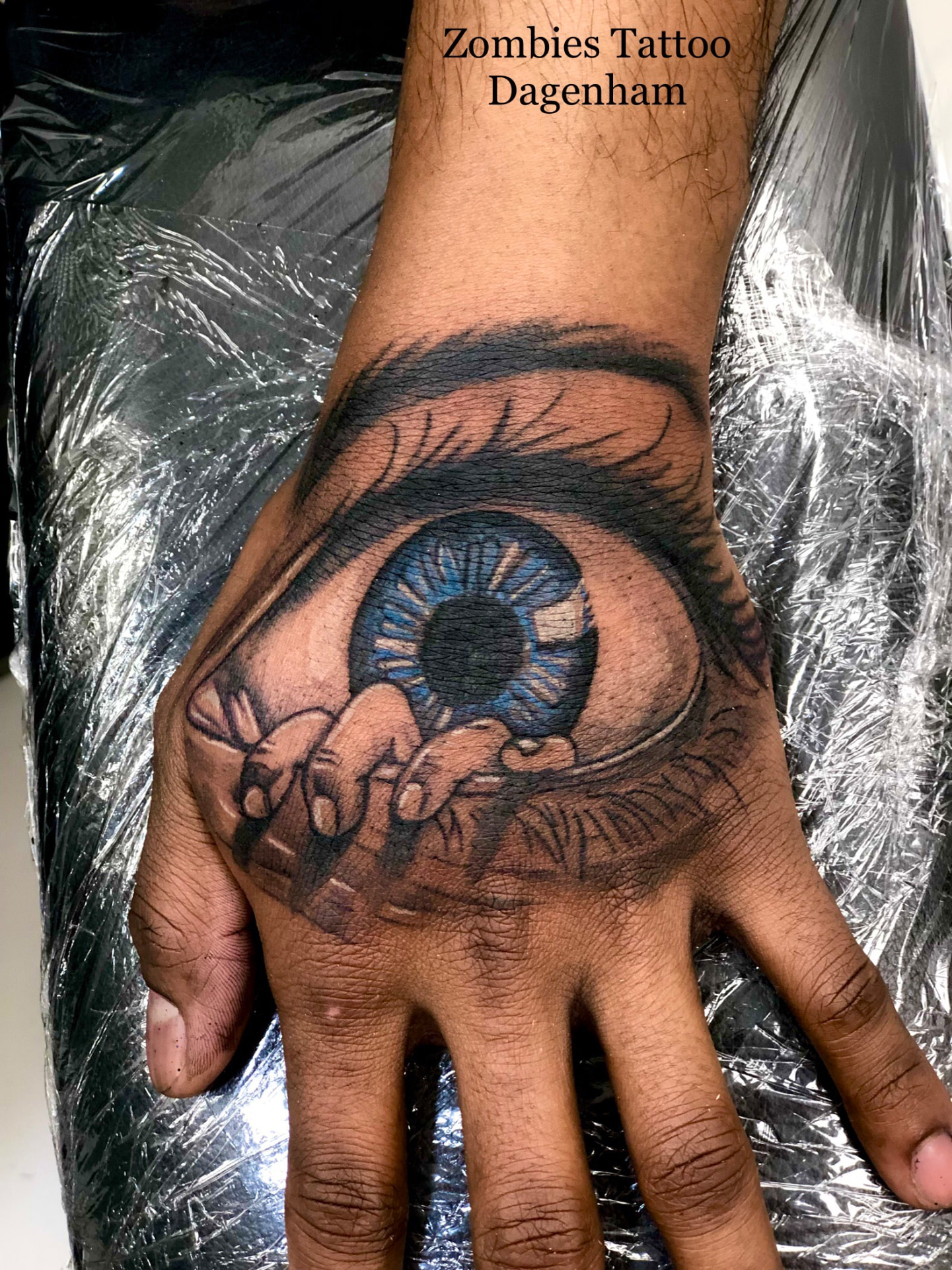 Black and grey realistic eye tattoo on a hand